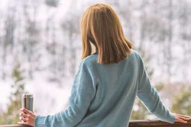Kadın bir termos şişe elinde bir kış ormanda arka planda