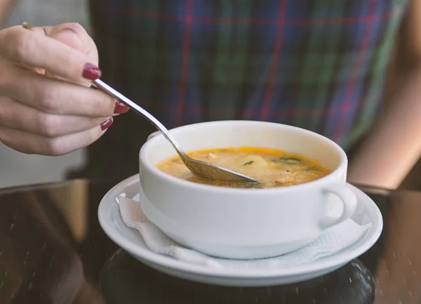 Woman's hand with the spoon while eating soup in the restaurant