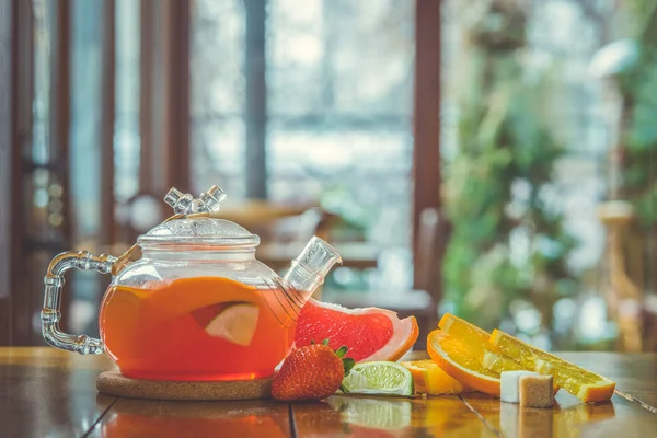 ガラス釜で赤いお茶と木の背景のカップをフルーツ — ストック写真