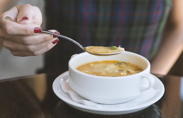 Woman\'s hand with the spoon while eating soup in the restaurant