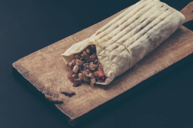 Hünkar kesme tahtası üzerinde olduğunu. Shawarma et, soğan, marul ile siyah bir arka plan üzerinde yatıyor.