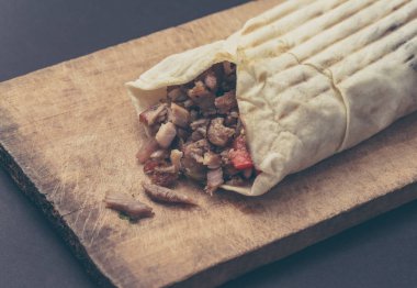Hünkar kesme tahtası üzerinde olduğunu. Shawarma et, soğan, marul ile siyah bir arka plan üzerinde yatıyor.