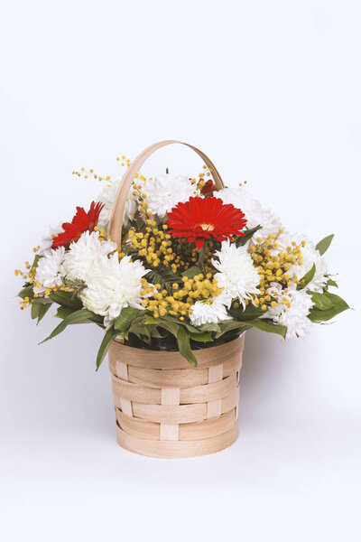 Colorful flower bouquet arrangement in basket on white.