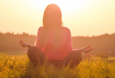 Gün batımında yoga yapan bir kadının arka ışığı.