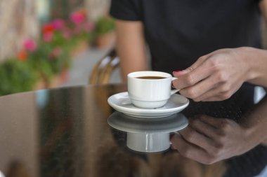 Kahve dükkanının arka planında, ahşap sehpanın üzerinde beyaz kahve fincanı.