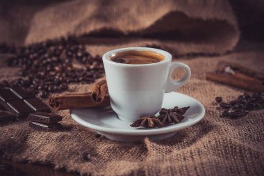 beyaz fincan kahve süt ve Aromatik baharatlar ile karanlık yol: tarçın, Yıldız anason, dilim limon ve kahve fasulye çuval bezi, peçeteye kurutulmuş