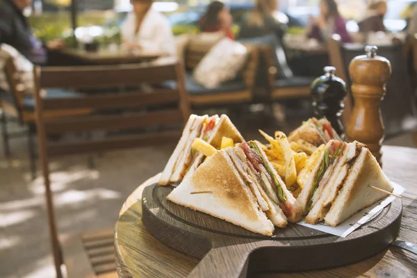 Club sandwich on wooden board on a table in a cafe