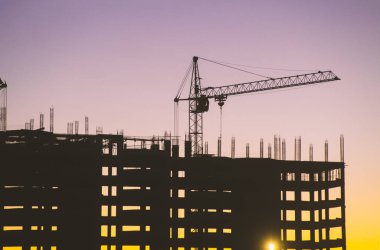 Endüstriyel makine ve inşaat vinç. Vinçler ve gökdelen yapım aşamasında, şehir manzarası, günbatımı, gündoğumu bina inşaat alanı altında.