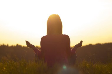 Gün batımında yoga yapan bir kadının arka ışığı.