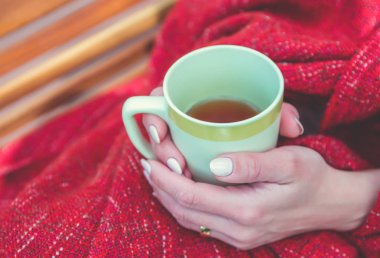 Genç kız ekose elinde çay ile sarılmış