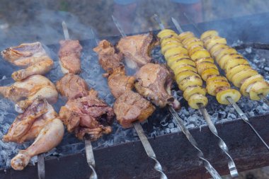 Domuz eti, tavuk eti ve patatesler dumandaki barbeküde şiş üstünde