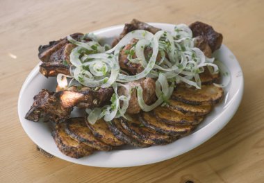 domuz şiş kebap ve ahşap bir masa üzerinde beyaz bir tabak patates