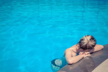 Güneşli bir günde havuzda dinlenen güzel genç bir kadın.
