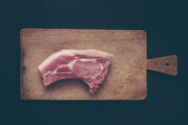 Сырое мясо на деревянной доске и черном фоне — стоковое фото