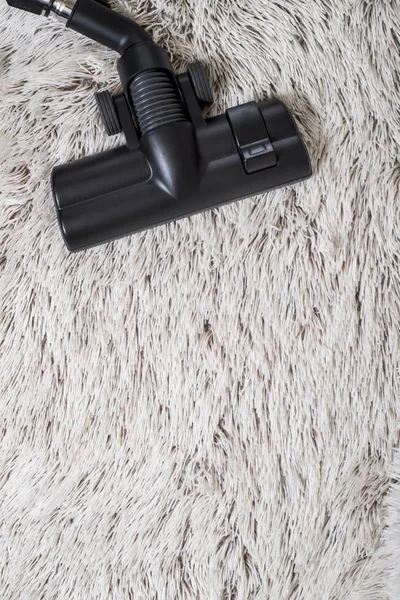 Bir kalın kazık beyaz carpet.still hayat koyu tonu vakumlama sırasında kullanılan modern elektrikli süpürge Başkanı yakın çekim.