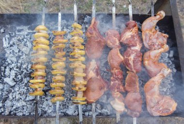 Domuz eti, tavuk eti ve patatesler dumandaki barbeküde şiş üstünde