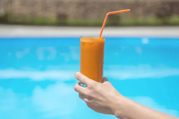 Suco em um copo na mesa de madeira junto à piscina. — Fotografia de Stock