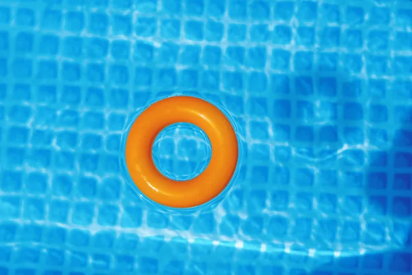 orange Inflatable ring floating in swimming pool on sunny day, top view