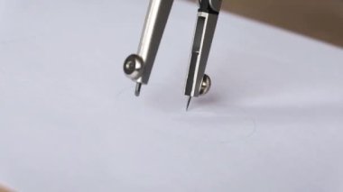 close-up footage of woman drawing with compass on white paper