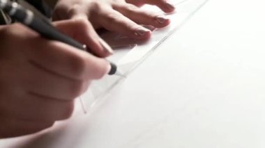 close-up footage of woman drawing with ruler on white paper