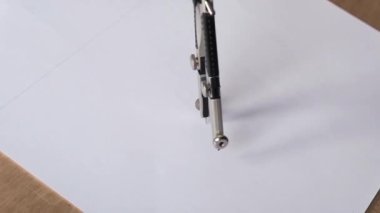 close-up footage of woman drawing with compass on white paper