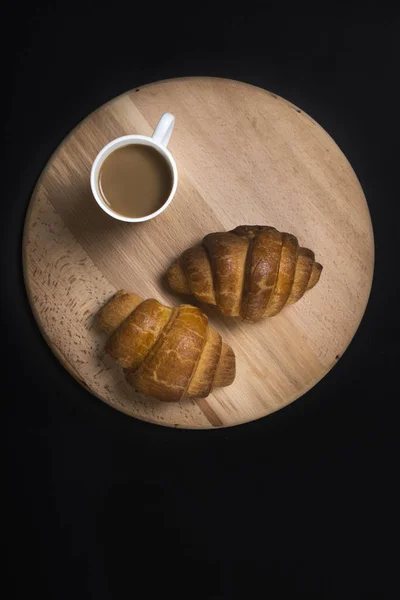 Croissants recién horneados en tablero de madera con taza de café en b — Foto de Stock