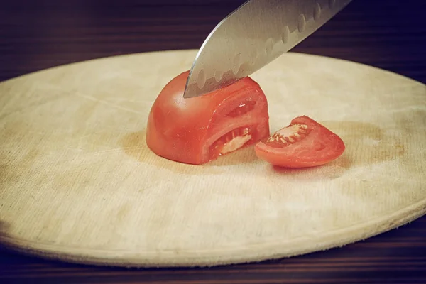 Cocinar cortando un tomate en un escritorio de madera — Foto de Stock