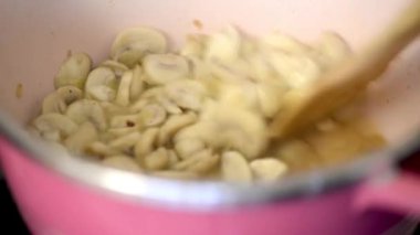 kişi bir tencerede doğranmış mantar pişirme