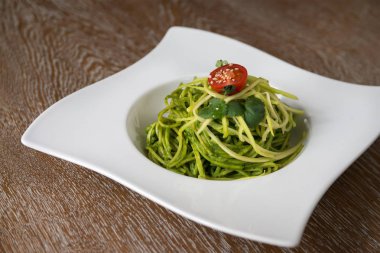 Tahta masada peynirli ve domatesli ıspanaklı spagetti.