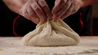 Baker kneading dough for pizza calzone preparation. Chef cook making dough for baking pie on wooden table. Process preparation homemade pastry. Cooking khachapuri, food concept