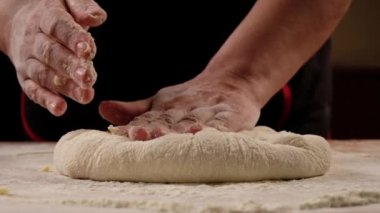 Baker kneading dough for pizza calzone preparation. Chef cook making dough for baking pie on wooden table. Process preparation homemade pastry. Cooking khachapuri, food concept