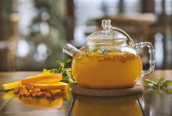 sea-buckthorn tea in a teapot on a wooden table