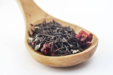 beyaz arka plan üzerinde izole ahşap bir kaşık üzerinde ahududu ile aromatik siyah kuru çay