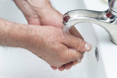 yaşlı adam banyoda ellerini yıkıyor