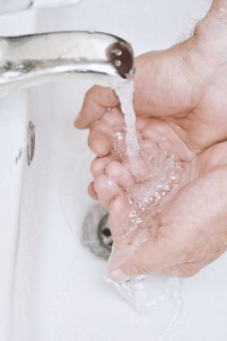 yaşlı adam banyoda ellerini yıkıyor