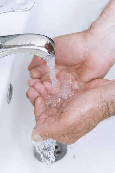 old man washes his hands in the bathroom