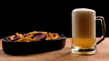 bira ve ahşap bir arka plan üzerinde patates ile kızarmış sosis ile bir bardak köpük. Oktoberfest.