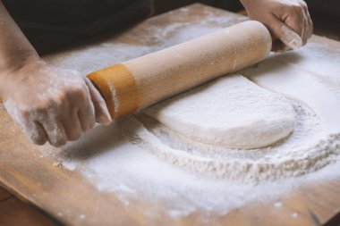 Fırıncı pizza hazırlama için hamur yoğurunur. Şef aşçı ahşap masada pasta pişirme için hamur yapma. Süreç hazırlık ev yapımı pasta. Pişirme makarna, spagetti, khachapuri, gıda konsepti