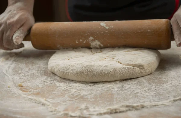 Baker kneading dough for pizza  preparation. Chef cook making dough for baking pie on wooden table. Process preparation homemade pastry. Cooking pasta, spaghetti,khachapuri, food concept