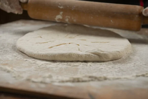 Baker kneading dough for pizza  preparation. Chef cook making dough for baking pie on wooden table. Process preparation homemade pastry. Cooking pasta, spaghetti,khachapuri, food concept