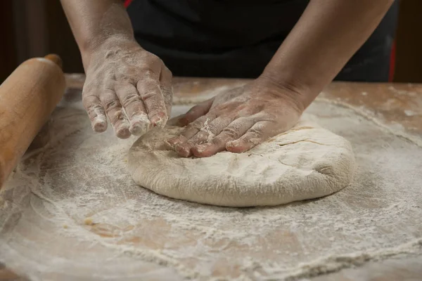 Fırıncı pizza hazırlama için hamur yoğurunur. Şef aşçı ahşap masada pasta pişirme için hamur yapma. Süreç hazırlık ev yapımı pasta. Pişirme makarna, spagetti, khachapuri, gıda concep