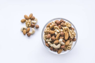 Beyaz bir arka plan üzerinde bir kapta karışık fındık.