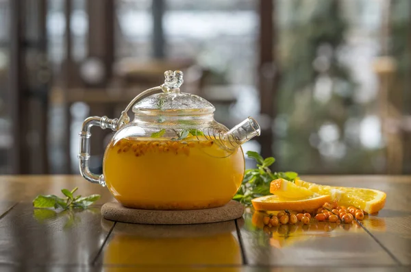 sea-buckthorn tea in a teapot on a wooden table