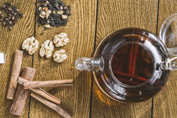 Té con canela en una tetera sobre una mesa de madera . — Foto de Stock