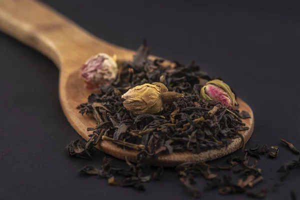 Αρωματικό Μαύρο Ξηρό Τσάι Ροδολουλούδια Μια Ξύλινη Κουτάλα Απομονωμένη Μαύρο — Φωτογραφία Αρχείου