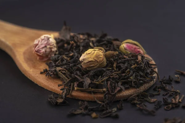 Αρωματικό Μαύρο Ξηρό Τσάι Ροδολουλούδια Μια Ξύλινη Κουτάλα Απομονωμένη Μαύρο — Φωτογραφία Αρχείου