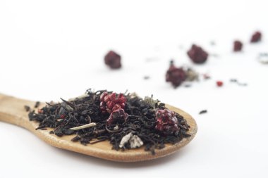 beyaz arka plan üzerinde izole ahşap bir kaşık üzerinde ahududu ile aromatik siyah kuru çay