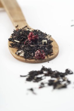 beyaz arka plan üzerinde izole ahşap bir kaşık üzerinde ahududu ile aromatik siyah kuru çay