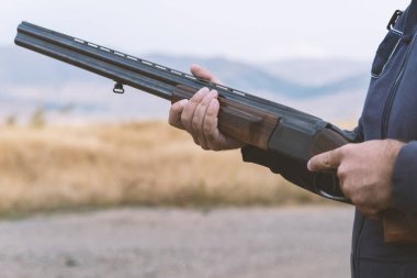 Erkek avcı av tüfeğiyle avlanmaya hazır. Avcı tüfeğini tutuyor..