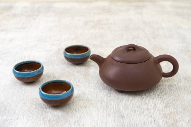 Kahverengi kil çaydanlık ve hafif ahşap zemin üzerinde fincanlar